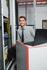 Young man is standing next to the racks with computer equipment