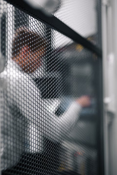 Young man is standing next to the racks with computer equipment