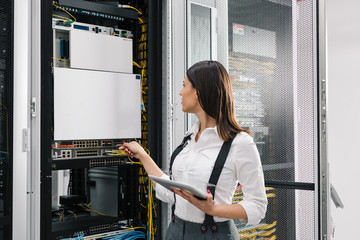 Technician using tablet pc while analysing server in large data center