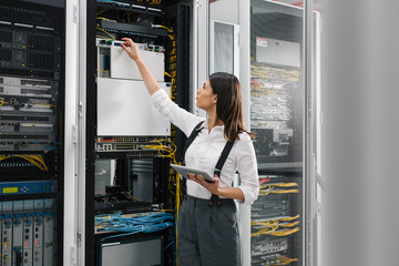 Technician using tablet pc while analysing server in large data center