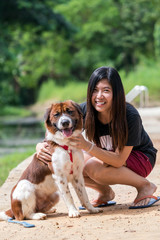 The asian women with Mixed breed dog in brown with white color standing in the resort, Lover and animal with nature concept