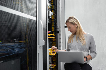 Portrait of technician working on laptop in server room
