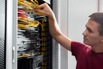 Young man is standing next to the racks with computer equipment