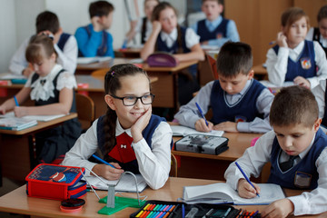 Elementary school students at a lesson in school writing in notebooks