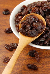 Black raisins on a wood spoon