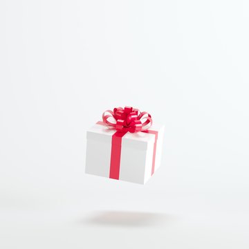White gift box with red ribbon floating on white background. minimal christmas concept idea.