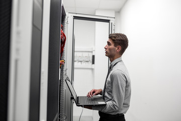 Young business man with laptop working in data center