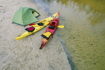 Rafting on kayaks. A tent camp stands on the river bank.