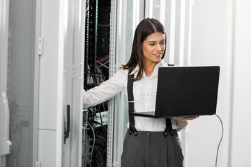 Portrait of technician working on laptop in server room