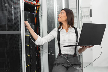 Portrait of technician working on laptop in server room