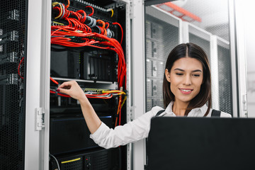 Portrait of technician working on laptop in server room