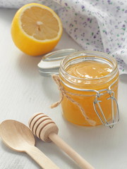 Glass jar full of  lemon curd with wooden spoons upon rustic table. Vertical. Selective focus.