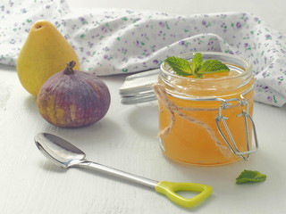 Glass jar full of  lemon curd with cute spoon, fig and fresh lemon upon rustic table. Selective focus.
