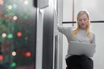 Portrait of technician working on laptop in server room