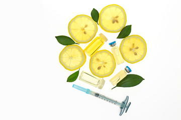 Vitamin C. Serum with Vitamin C, ampoule, syringe, lemon slices and lemon leaves on white...