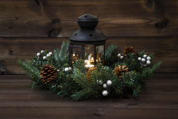 Fototapeta na wymiar Decorated Advent wreath with a black lantern with a burning tea light and open door on a wooden background
