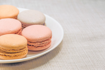 Delicious cake macaroons on plate on light background, close up