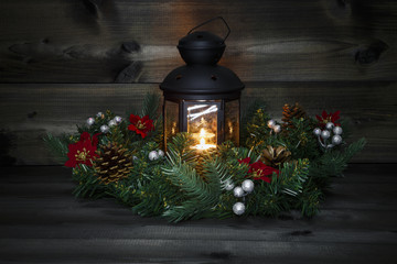 Fototapeta na wymiar Decorated Advent wreath with a black lantern with a burning tea light on a wooden background with a magic atmosphere