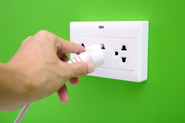 Electric power plug in a hand and inserting into power wall socket