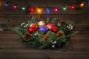 Decorated Advent wreath with different Christmas balls on a wooden background and a shining multicolored garland