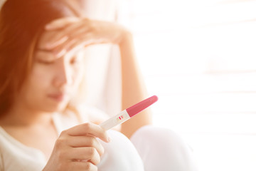 Fototapeta premium Selective focus Pregnancy test positive result on hand of woman in her bedroom,Blurred background.