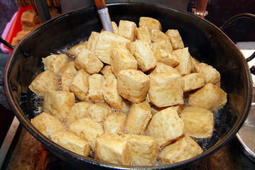 Stinky tofu fried with oil in a big pot         