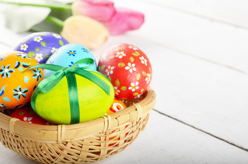Rustic style painted easter eggs in basket on white table