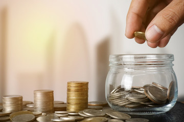 Money saving concept - Male hand putting money coin to jar