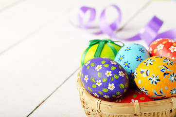 Rustic style painted easter eggs in basket on white table