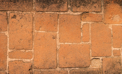 The background image of the surface of base of an ancient building made of a red brick. 