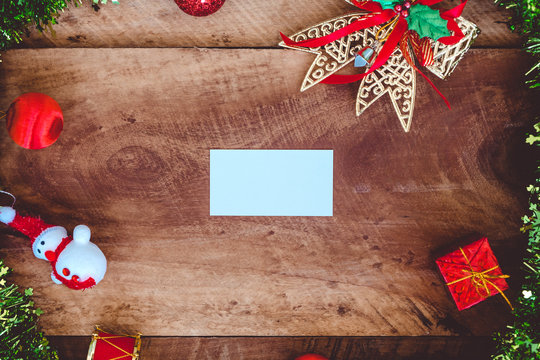 Top view mockup image of white blank name card with christmas decorations on wooden background
