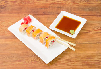 Sushi with salmon and chopsticks on dish and condiments