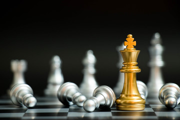 Gold king in chess game face with the another silver team on black background (Concept for company strategy, business victory or decision)