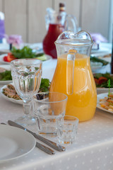 фруктовый сок в прозрачном кувшине и чистые столовые приборы