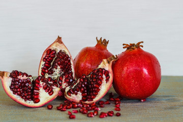 Ripe pomegranate fruits are whole and halved with scattered around the grains.