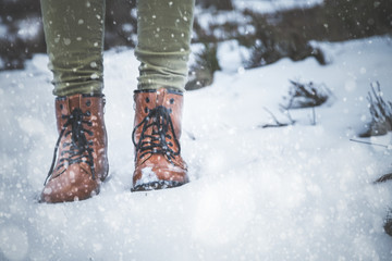 Girl in boots on the snow expecting winter.