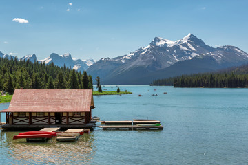 Beautiful Maligne Lake with a boathouse and canoes and snow covered mountains, Jasper, Canadian Rockies.