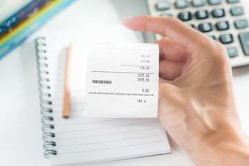 Grocery shopping list in hand with calculator and pencil - money account management concept