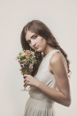 Girl with long hair and a bouquet of flowers in a glass