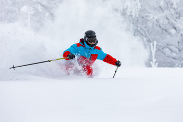 A skier is riding downhill in the deep snow.