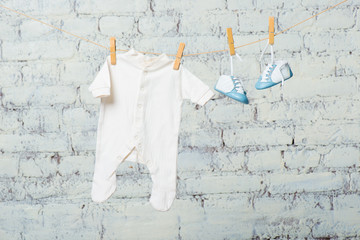 Children's white body and blue shoes on a rope against a white brick wall.