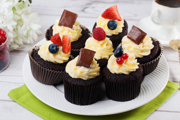 chocolate cupcakes with white cream blueberries strawberries