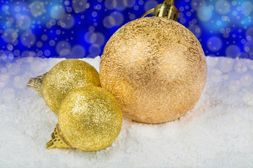 Golden Christmas decorations on snow in the form of balls.