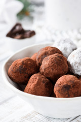 Chocolate truffles in white bowl on white table. Closeup view, selective focus