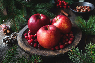 Red apples, cranberries and fir tree branches. Christmas still life. Winter wallpaper. Horizontal view