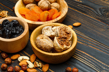 dried fruits figs, apricots, plums and nuts on wooden background