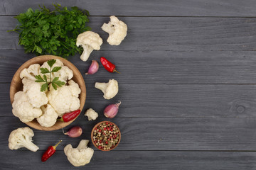 Fresh cauliflower with garlic and chili peppers on black wooden background with copy space for your text. Top view