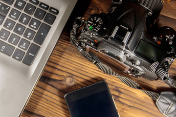 Laptop, smart phone and photo camera on wooden background