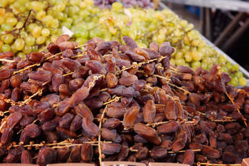 Dried dates on twigs lie on the counter next to the grapes