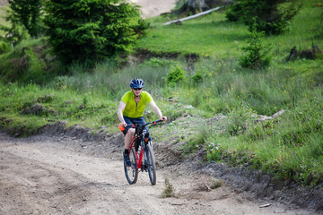 Naklejka premium man rides the bicycle up in the mountains